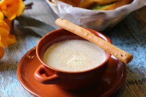 Close-up of a delicious cream soup with a breadstick served in a rustic, cozy setting.