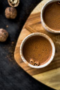 Warm cinnamon hot chocolate in rustic cups on a wooden board, perfect for cozy evenings.